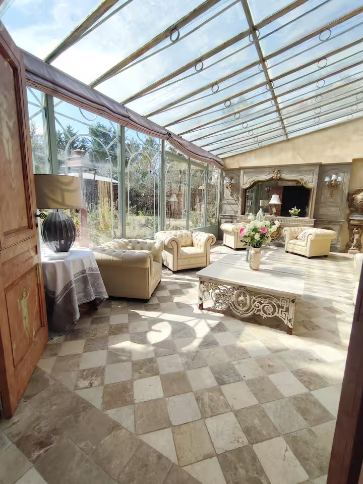 Elegant sunroom with vintage furniture and glass roof.