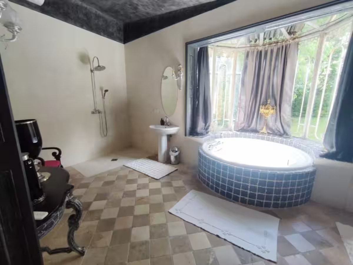 Salle de bain avec baignoire ronde et grande fenêtre.