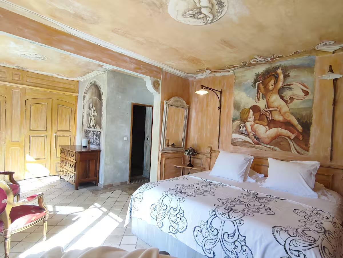 Chambre avec fresques et lit double élégant.