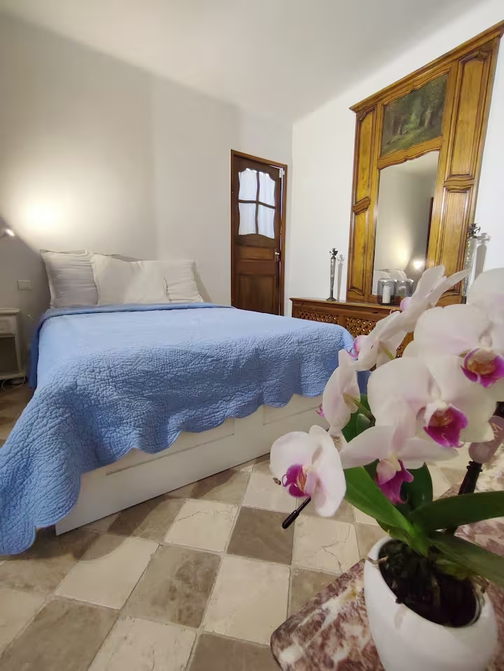 Chambre avec lit bleu et orchidées blanches.