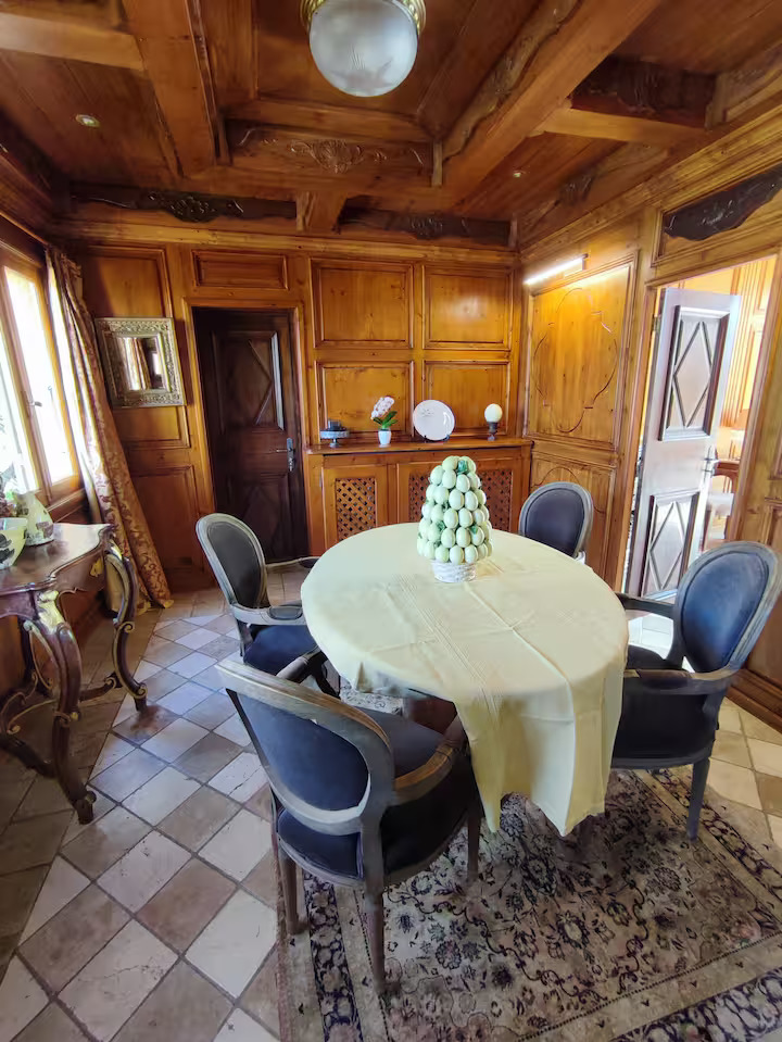 Salle à manger rustique avec table ronde et chaises.